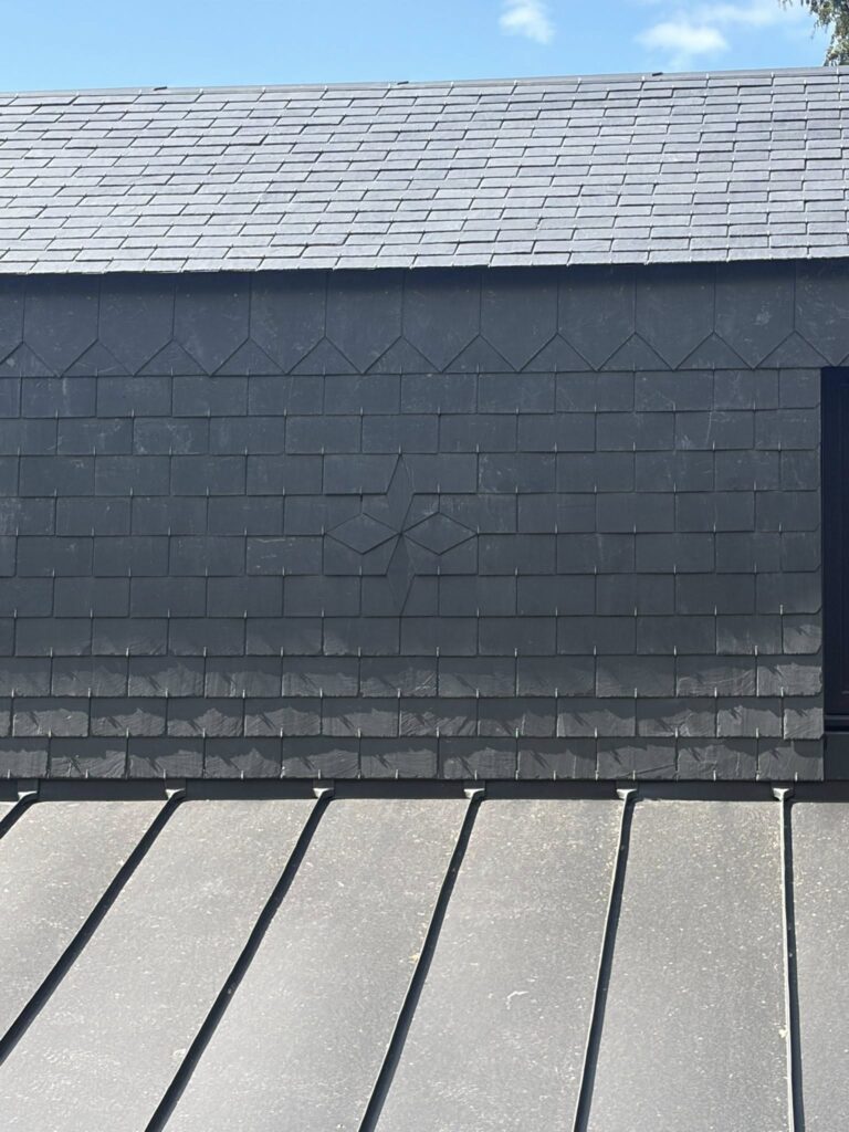 Détail d'un bardage en zinc à joint debout posé sous une toiture en ardoise par Houisse Couverture