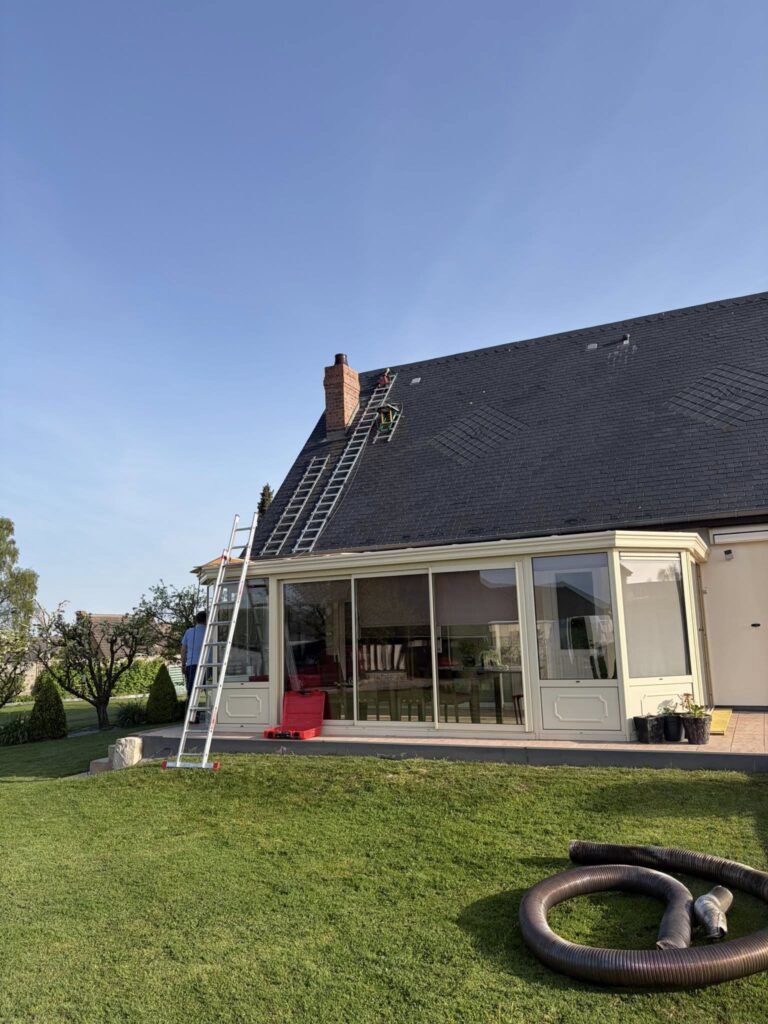 Chantier de rénovation de toiture en cours sur maison avec véranda et échelles d'accès en Seine-Maritime
