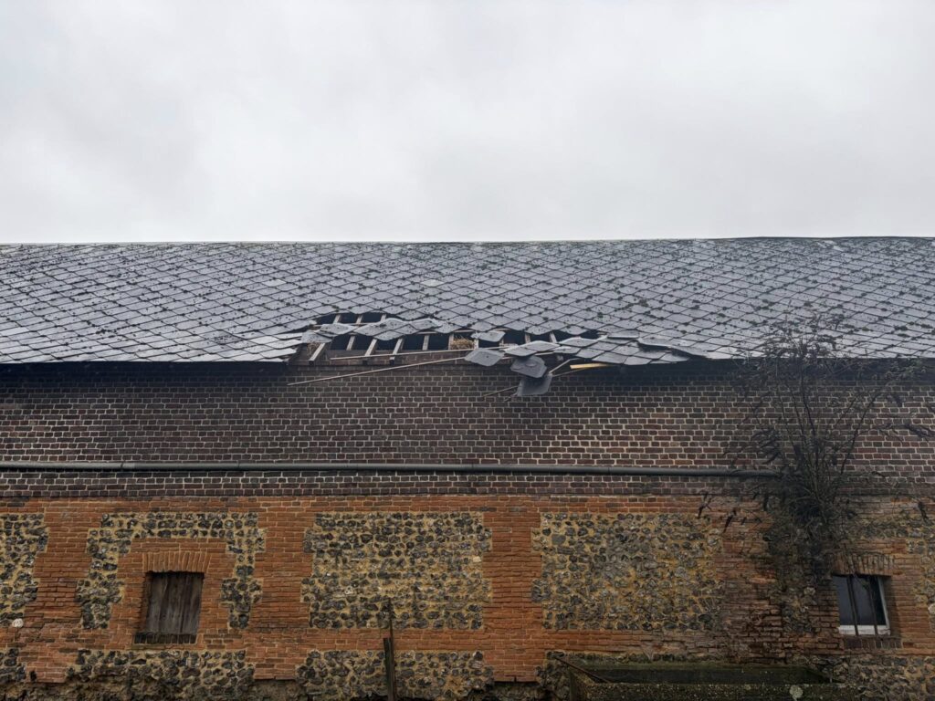 Grange ancienne avec toiture ardoise partiellement effondrée nécessitant une rénovation lourde de charpente