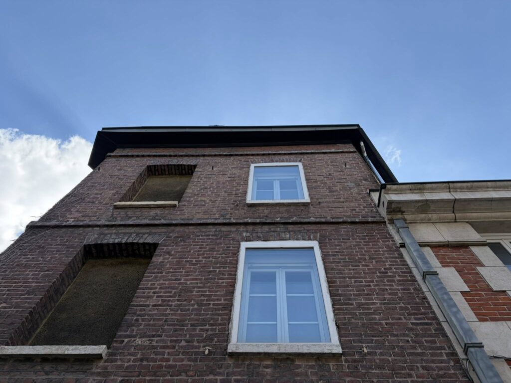 Zinguerie noire et descente de gouttière sur façade en briques d'une maison en Seine-Maritime